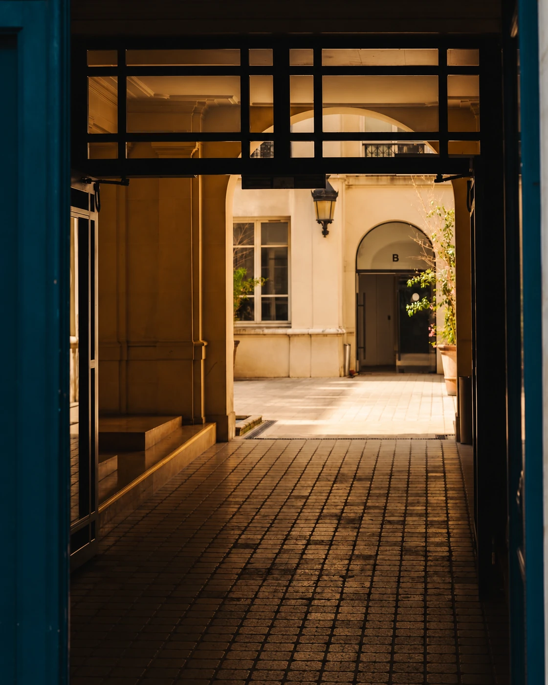 A warm sunlit courtyard framed by a deep teal doorway.