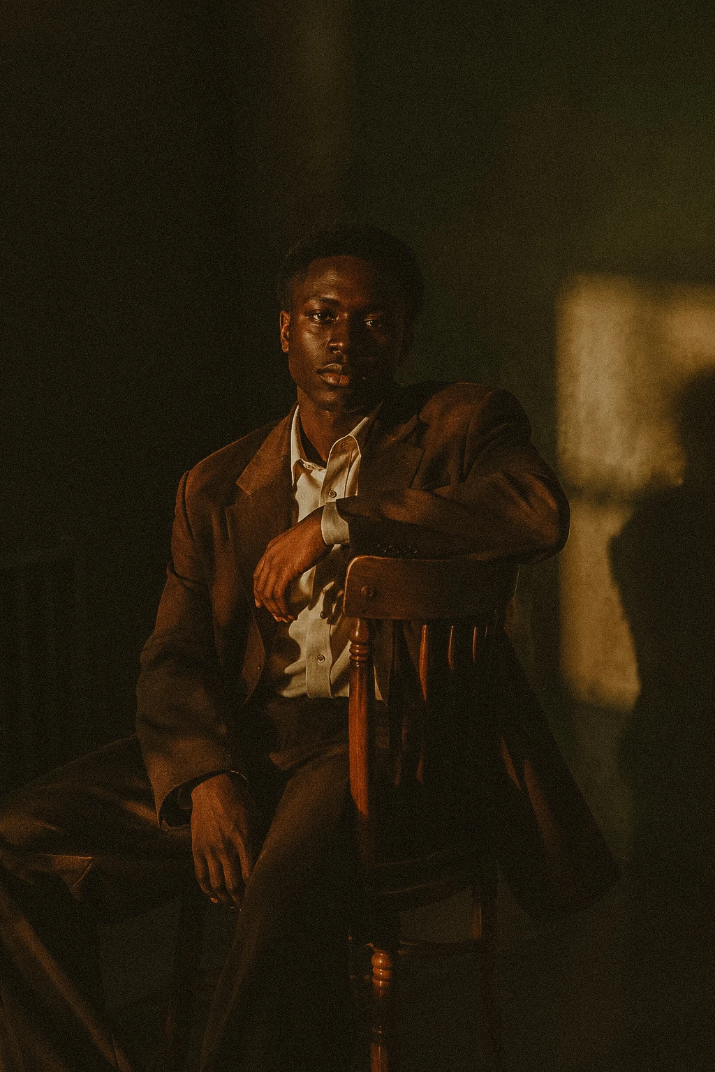 Seated portrait in brown tailoring and warm directional light.